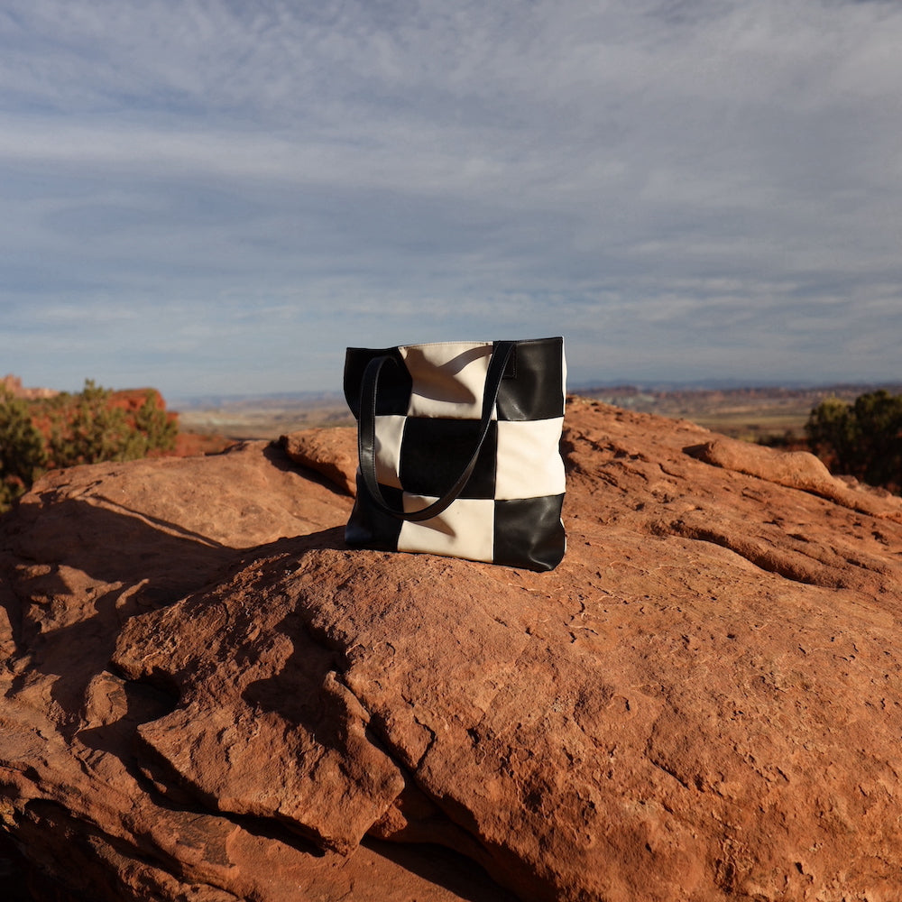 Black and white checker tote bag made from vegan leather in a desert landscape