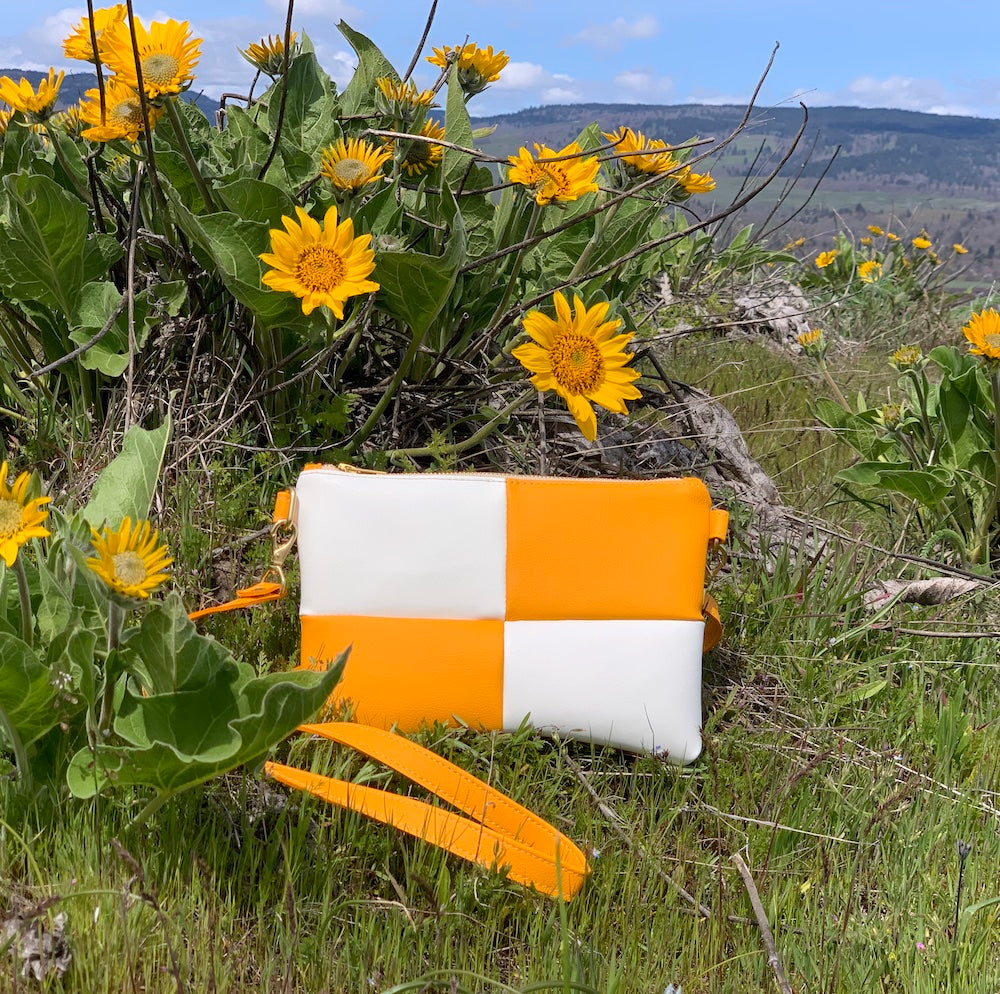 Marigold yellow and white checker crossbody bag placed among yellow flowers
